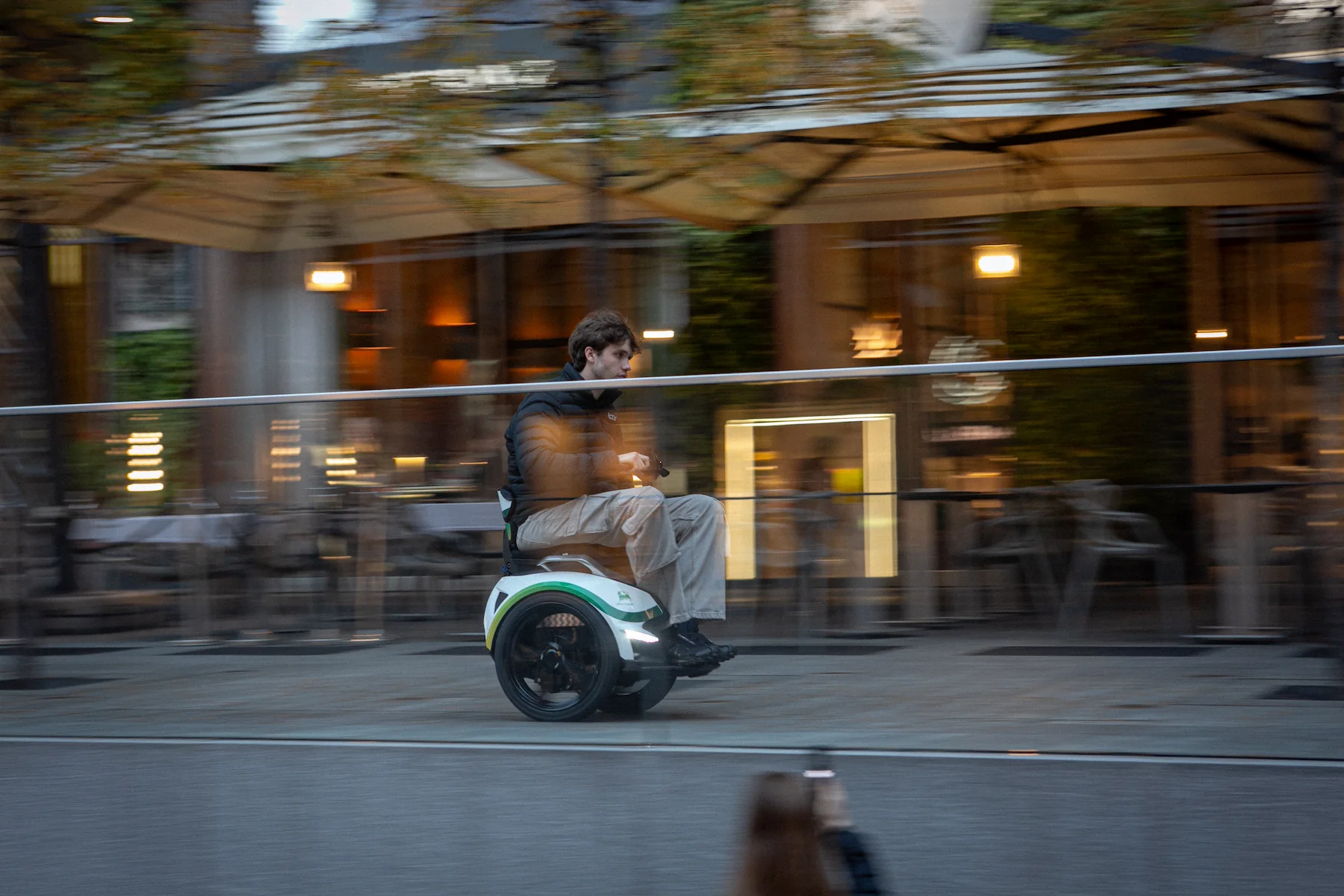 Man rijdt op wit-groene balansrolstoel langs een terras voor een rolstoelvriendelijke vakantie
