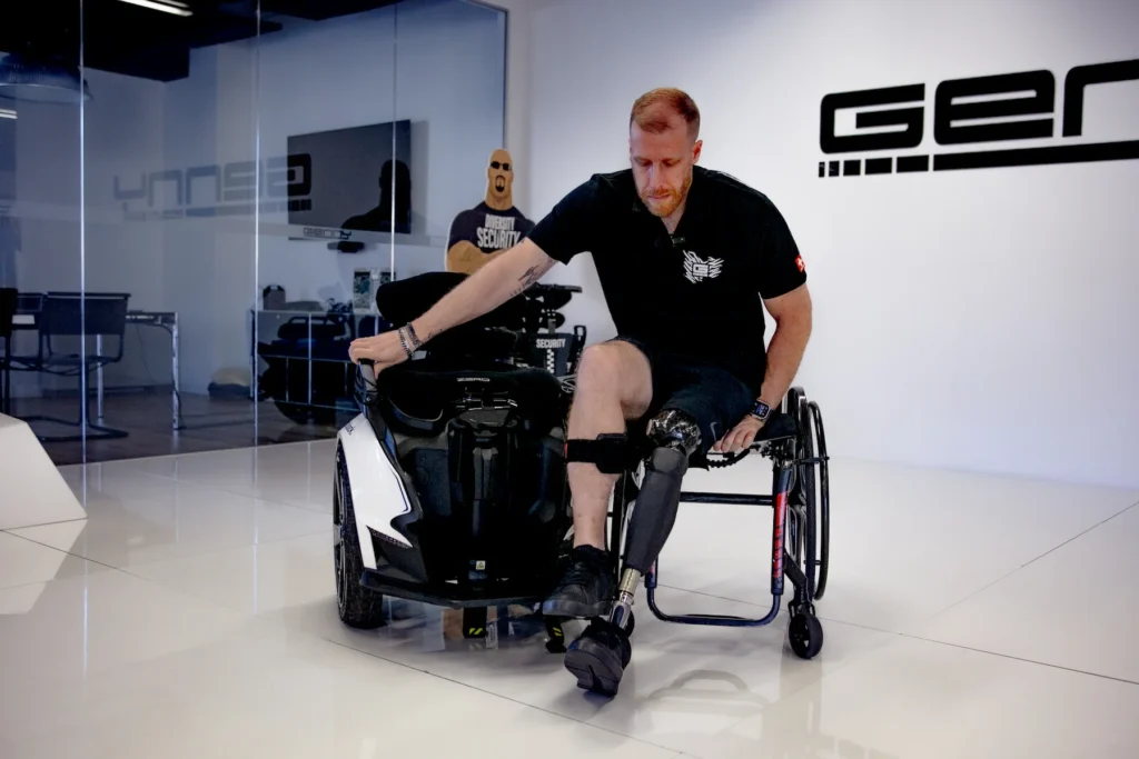 Man met een beenprothese stapt over van een rolstoel naar de Genny Zero tijdens een presentatie in de Genny Factory.